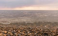 Rain clouds over the sea at sunset. Pebbles on the beach close-up, clouds colored the shades of pink and little waves on Royalty Free Stock Photo