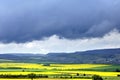 Rain clouds pull over rapeseed fields and mountains Royalty Free Stock Photo