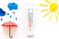 Rain concept. Weather thermometer near umbrella on white background top view copy space