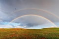 After the rain, a double rainbow over the fields of lush grass in the fields Royalty Free Stock Photo