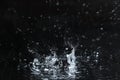 Rain drop falling down into puddle on dark Royalty Free Stock Photo