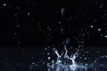 Rain drop falling down into puddle on dark Royalty Free Stock Photo