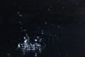 Rain drop falling down into puddle on dark Royalty Free Stock Photo