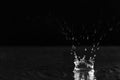 Rain drop falling down into puddle on dark background Royalty Free Stock Photo