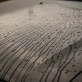 Rain droplets create linear patterns on a metallic surface, possibly a car hood. The Royalty Free Stock Photo