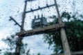 Rain droplets on surface of car glass with blurred electric pole with transformer and fuse background through window glass of car Royalty Free Stock Photo