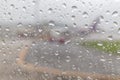 Rain drops on airplane window glass and blurred airport runway i Royalty Free Stock Photo