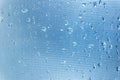Rain drops on the blue glass bokeh background, shiny raindrops on a glass surface, water drops in a swimming pool closeup Royalty Free Stock Photo