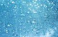 Rain drops on the blue glass bokeh background, shiny raindrops on a glass surface, water drops in a swimming pool closeup Royalty Free Stock Photo