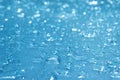 Rain drops on the blue glass bokeh background, shiny raindrops on a glass surface, water drops in a swimming pool closeup Royalty Free Stock Photo