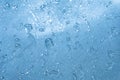 Rain drops on the blue glass bokeh background, shiny raindrops on a glass surface, water drops in a swimming pool closeup Royalty Free Stock Photo