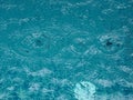 Rain drops falling blue water in pool background ripples on the surface texture, glittering bokeh abstract Royalty Free Stock Photo