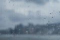 Windowpane with rain drops through which the panorama of the big city and the sky with clouds is visible, the modern city