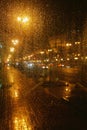 Rain drops on glass surface with bokeh night city lights from lanterns Royalty Free Stock Photo