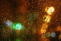 Rain drops on glass surface with bokeh night city lights from lanterns Royalty Free Stock Photo