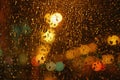 Rain drops on glass surface with bokeh night city lights from lanterns Royalty Free Stock Photo