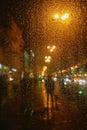 Rain drops on glass surface with bokeh night city lights from lanterns Royalty Free Stock Photo