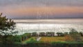 Rain drops on a large panoramic window looking out to sea on a stormy, cloudy day as sunshine briefly hits the sea