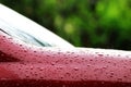 Rain drops on the red car surface, water droplets wet on red car`s surface hood, water rain drop wet on red texture, water stain Royalty Free Stock Photo