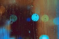 Rain drops run down the window with colorfull lights of the nitht city. Abstract background of night city life. Royalty Free Stock Photo