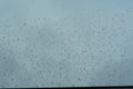 Rain drops sticking on the window pane in heavy downpour with cloudy sky on the background Royalty Free Stock Photo