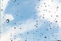Rain drops, water drops of rain on a window glass with blurred sky clouds
