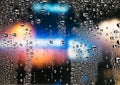 Rain drops on the window. Colorful street lights on the rain. Blurred abstract background. Royalty Free Stock Photo