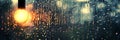 Rain drops on window glass with blurred background of a glowing light bulb in warm colors Royalty Free Stock Photo