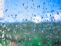 Rain drops on the window glass. Blurred background with house, greenery, clouds and blue sky - selective focus Royalty Free Stock Photo