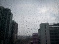 Rain drops on window glass with blurred skyscraper building in the city Royalty Free Stock Photo