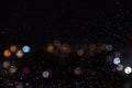 Rain drops on window at night with street bokeh blurred lights. Defocused colorful lights abstract background Royalty Free Stock Photo