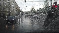 Rain drops on a window overlooking a road with passing cars