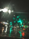 Rain drops on window with road light bokeh, water drop on the glass, night storm raining car driving concept. Night car