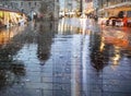 rain drops on window vitrine glass view on street ,rainy city wet pavement medieval houses people walk with umbrellas night light Royalty Free Stock Photo