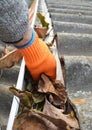 Rain Gutter Cleaning from Leaves in Autumn with hand. Roof Gutter Cleaning Tips. Royalty Free Stock Photo
