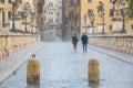 Rain in the historic center of Rome in Italy. Two people back to back walking under the storm. Sant Angelo bridge