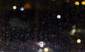 Rain outside. Drops of water on a pane at night. Bad weather in the city. Lantern light defocused in beautiful bokeh