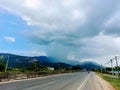 Rain pouring down on the distant mountain with asphalt road foreground