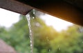 Rain pouring off roof with rays of sunlight