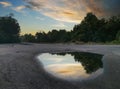 After rain puddle by the road with sky reflection on the surface Royalty Free Stock Photo