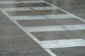 Rain at a row of white liraining at a white lines of crosswalk on city stree.The rainy season