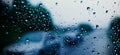 Rain shower on car windshield or car window and blurry road in background