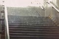 Rain-soaked metro exit stairs with dramatic backlight and falling water in a moody urban scene from Bucharest Romania Royalty Free Stock Photo