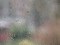 Rain-sprinkled window pane glittering on a moody bokeh backgorund