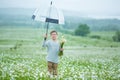 Rain and sunshine with a smiling boy holding an umbrella and running through a meadow of wildflowers dundelions chamomile daisy an