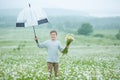 Rain and sunshine with a smiling boy holding an umbrella and running through a meadow of wildflowers dundelions chamomile daisy an