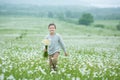 Rain and sunshine with a smiling boy holding an umbrella and running through a meadow of wildflowers dundelions chamomile daisy an