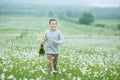 Rain and sunshine with a smiling boy holding an umbrella and running through a meadow of wildflowers dundelions chamomile daisy an