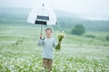 Rain and sunshine with a smiling boy holding an umbrella and running through a meadow of wildflowers dundelions chamomile daisy an