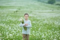 Rain and sunshine with a smiling boy holding an umbrella and running through a meadow of wildflowers dundelions chamomile daisy an